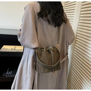 Detail of olive green suede bucket bag featuring long fringe and drawstring closure
