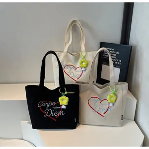 Detailansicht der Canvas-Tote-Bags mit Herz-Stickerei und gelben Blumenanhängern