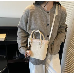 Detailed view of suede bucket bag with faux fur trim and cute plush biscuit charm