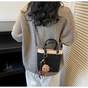 Detail of suede bucket bag featuring plush faux fur trim and cute cookie bag charm