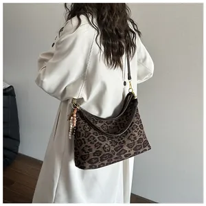 Detail of leopard print tote bag featuring brown leather straps and boho tassel charm