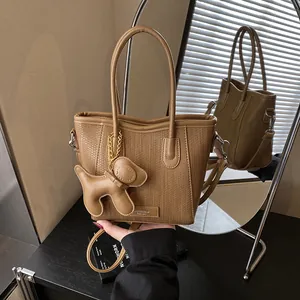 Brown woven texture tote bag with puppy charm and detachable shoulder strap in a mirror view