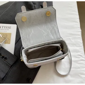 Detail of light gray textured crossbody box bag showing magnetic closure and interior