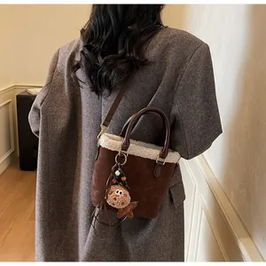 Detail view of coffee suede bucket bag with white faux fur trim and gingerbread man charm
