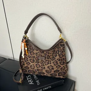 Detail of vintage leopard print hobo bag with leather straps and wooden bead charm