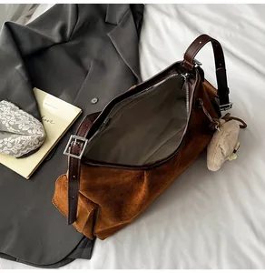 Detailansicht der dunkelbraunen Wildleder-Schultertasche mit Lederriemen und Anhänger