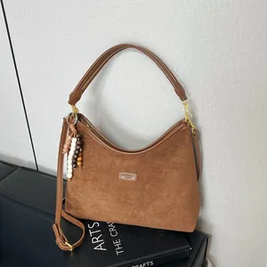 Detail view of brown suede hobo bag with bead tassel charm and adjustable strap