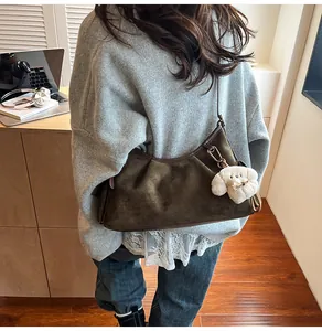 Detail der olivgrünen Wildleder-Schultertasche mit einem süßen Plüschhund-Anhänger