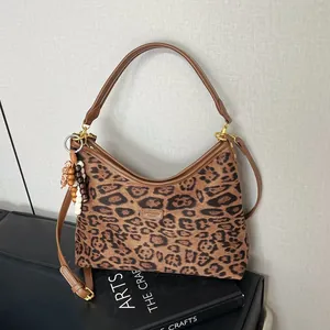 Detail of leopard print tote featuring brown leather handles and decorative wood bead charm