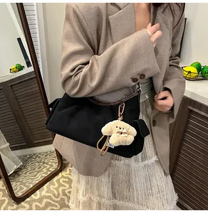 Detail der matten Wildledertasche mit Lederbesatz und süßem Welpenanhänger-Dekor