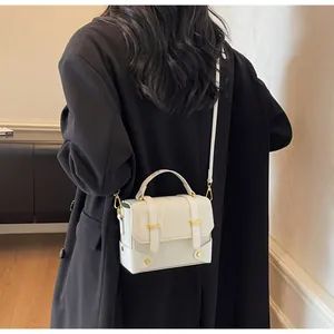 Detailed back view of a white patent leather crossbody bag on a black blazer
