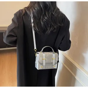 Silver wrinkled crossbody bag with gold hardware details on a female model