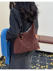 Detail of a large brown suede tote bag with flower charm decoration and logo print