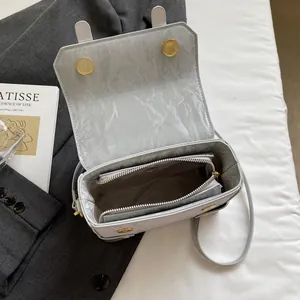 Light gray textured box handbag with magnetic closure and crossbody strap in modern style