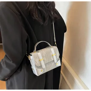 Detail view of silver crossbody bag with pleated texture and golden metal buckle accents