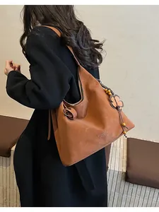 Detail view of caramel brown tote bag with decorative flower charm and wooden beads