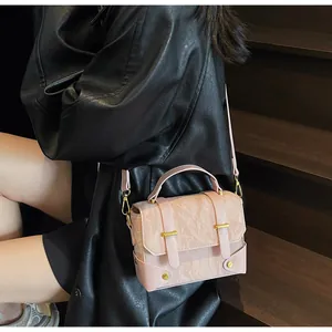 Detail of pink textured crossbody bag with gold buckles on dark wooden stairs