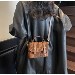 Detail of vintage brown shoulder bag with unique paper-fold texture and gold metal buckle