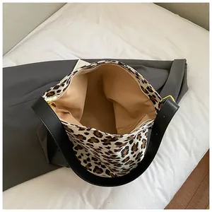 Macro detail of leopard print tote featuring wide black shoulder strap and gold zipper