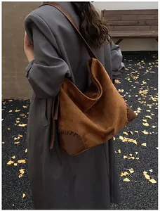Detail of brown suede patchwork hobo bag with hand-stitched leather corners and strap