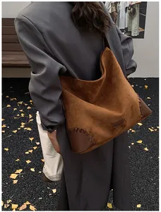 Detail of suede hobo bag with reinforced leather corners and artisan woven stitching