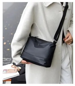 Close-up of a black nylon crossbody bag with an adjustable wide strap and round logo