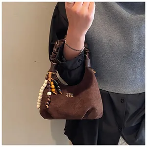 Detail view of brown faux suede dumpling bag with pleated handle and wood bead charm