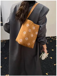 Dettaglio borsa tote in pelle scamosciata marrone con ricami di fiocchi di neve bianchi