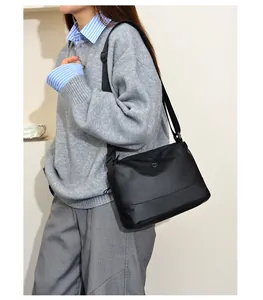 Detail of minimalist black nylon crossbody bag with adjustable strap and round logo