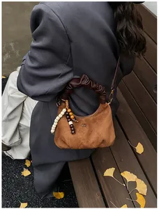 Detail of vintage brown suede crossbody bag with quilted pattern and beaded charm