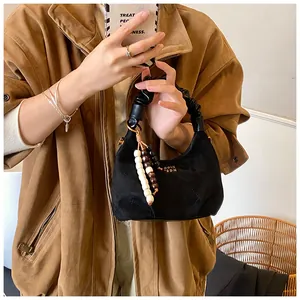 Detail of black quilted hobo bag featuring a gold logo and vintage wooden bead charm
