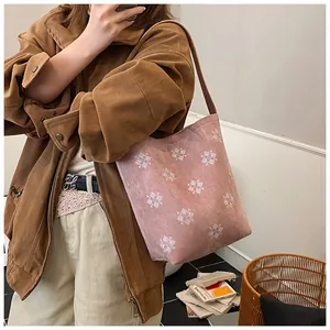 Dettaglio della borsa tote in camoscio rosa con ricamo a fiocco di neve bianco