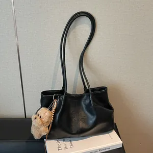Minimalistische zwarte kunstlederen draagtas met plooien en een pluche hondenbedeltje