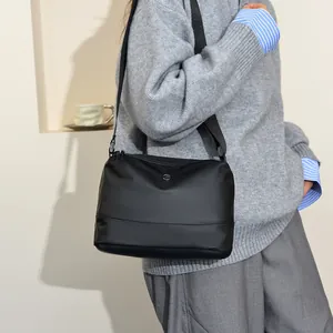 Minimalist black nylon crossbody bag with adjustable strap shown in a modern lifestyle setting
