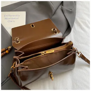Detailed interior view of brown leather shoulder bag with zipper pocket and golden hardware