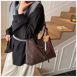 Detail view of large dark coffee hobo bag with teddy charm and metal chain link