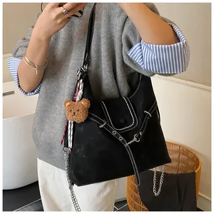 Detail of black matte Hobo bag featuring white contrast stitching and a cute bear charm