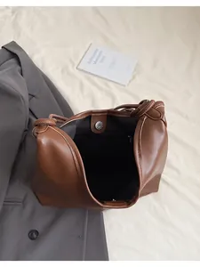 Detail view of brown leather tote showing magnetic closure and interior zipper pocket