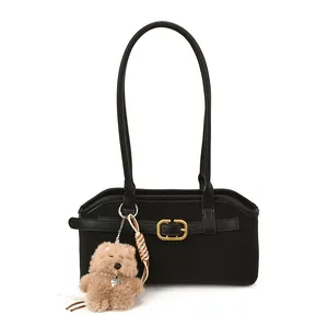 Retro black faux leather shoulder bag with gold buckle and plush dog charm on white background