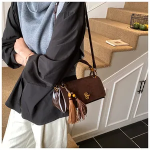 Detail view of coffee suede shoulder bag with long tassels and vintage gold metal twist lock