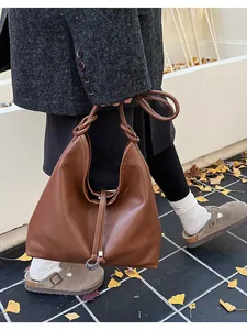 Detailed view of the dark brown leather hobo bag with knotted handle and metal charm