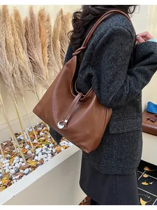Detail of soft brown faux leather hobo bag with metal ring and autumn aesthetic texture