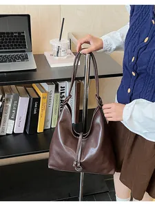 Detail of dark brown leather tote bag with metal ring and tassel on office desk