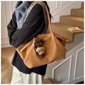 Détail du sac cabas plissé camel avec un pendentif ours mignon et une texture en cuir mat