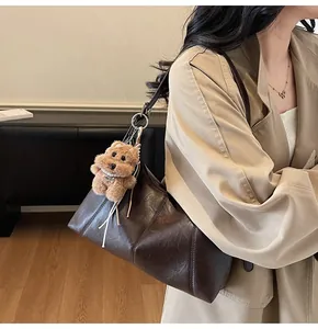 Dettaglio borsa tote marrone scuro con ciondolo a forma di orso indossata da modella