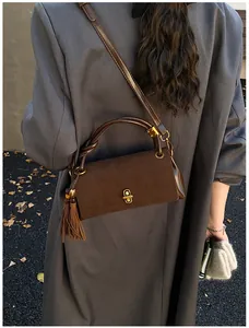Detail of dark brown suede shoulder bag featuring gold twist lock and long tassel decor