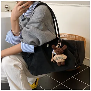 Détail d'un grand sac fourre-tout noir avec un joli pendentif en peluche d'ours marron