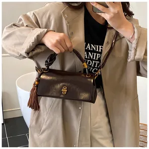 Close-up of a vintage brown shoulder bag with a gold metal lock and elegant tassel detail