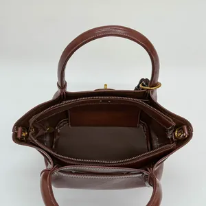 Brown leather tote bag with gold zipper and dual handles showing spacious inner storage