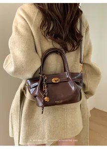 Detail of dark brown leather tote with a gold twist lock and woven tassel accent